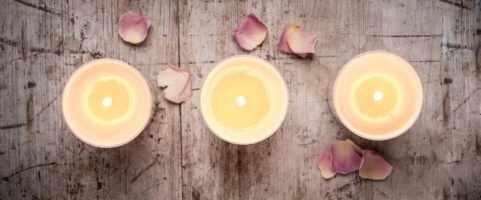 Styled shot of candles on a wooden board with scattered petals