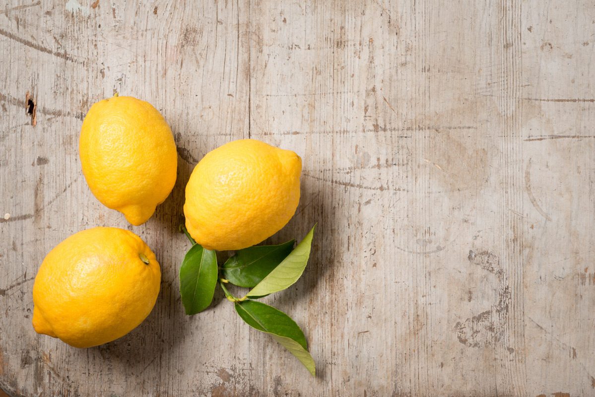 Three lemons and leaves on wood