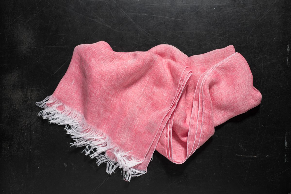 A Peach-Colored Hand Towel with White Fringes on Dark Surface