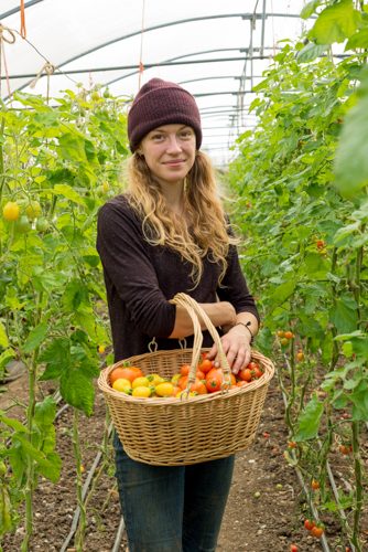 Smiling blonde girl holds wooden basket of organic produce