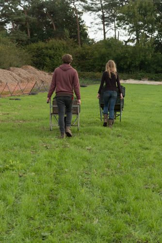 Man and woman push barrows of organic produce through field